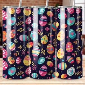 May include: Three stainless steel tumblers with an Easter egg design. The pattern includes eggs in pink, yellow, blue, and orange, with floral and leaf accents on a dark blue background. Each tumbler has a white straw.