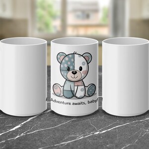 Peut inclure: Trois mugs en céramique blanche. Le mug central présente un motif d'ours en peluche de dessin animé en bleu, rose et blanc, avec le texte "Adventure awaits, baby !" Les deux autres mugs sont blancs unis.