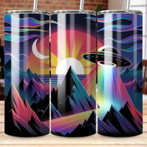 Puede incluir: Tres vasos de acero inoxidable con un diseño retro. El diseño presenta una puesta de sol, montañas, una luna creciente y un OVNI con un rayo arcoíris. La paleta de colores incluye tonos de rosa, naranja, azul y morado.