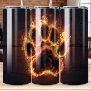 May include: A set of three stainless steel tumblers with a black wood grain design. Each tumbler features a fiery paw print graphic. The tumblers have a silver rim and a straw.