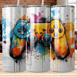 May include: Three stainless steel tumblers featuring a colourful abstract design of a video game controller. The design incorporates splashes of blue, yellow, orange, and red paint.