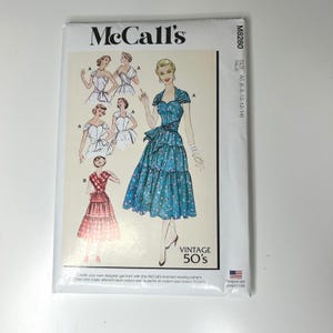 May include: A vintage McCall's sewing pattern featuring illustrations of 1950s dresses. The pattern packet displays a teal dress with a floral print and a tiered skirt. The text "VINTAGE 50's" is visible. Size A5 (6-8-10-12-14).