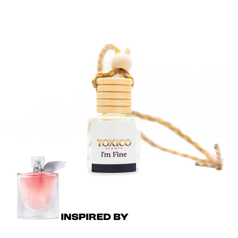 Puede incluir: Un ambientador de cristal transparente con tap&oacute;n de madera y cuerda, con el texto "TOXICO SCENTS I'm Fine". Tambi&eacute;n se ve un frasco de perfume rosa, con el texto "INSPIRED BY" debajo.