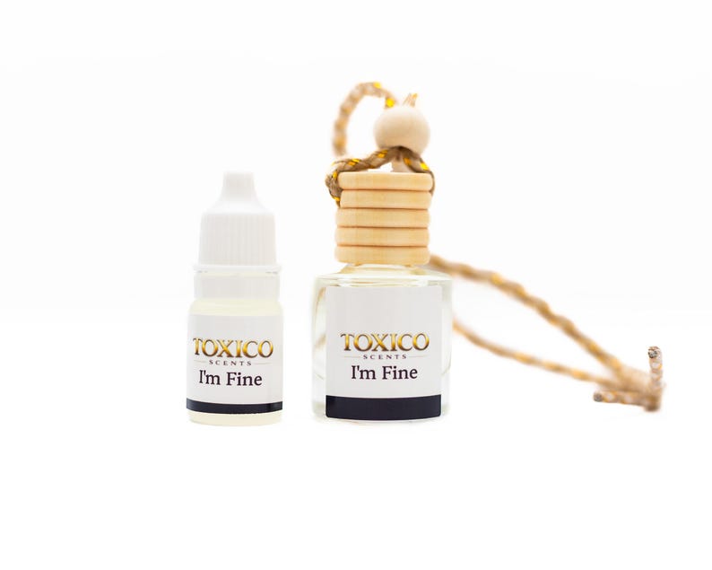 Puede incluir: Dos peque&ntilde;os frascos de vidrio de fragancia "TOXICO SCENTS". Uno es un peque&ntilde;o frasco con cuentagotas, el otro es un ambientador para coche con tapa de madera y cuerda. Ambos frascos tienen el texto "I'm Fine".