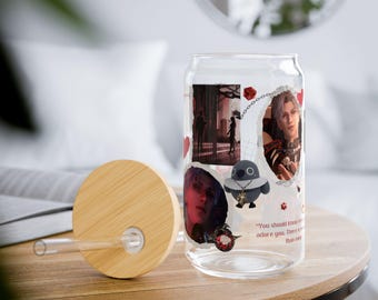 May include: A clear glass can with a bamboo lid and a straw. The can is decorated with images of characters from a video game, including a bird with a crown and a quote that reads "You should know my heart adores you. There's no one that can"