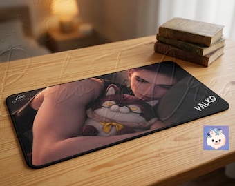 May include: A rectangular desk mat featuring a printed illustration of a person holding a plush toy with a yellow bow. The mat has a black border and the text VALKO printed in white on the right side. The surface is smooth with rounded corners.