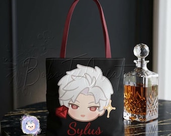 May include: Black tote bag featuring a cartoon character design, with burgundy handles and the name "Sylus" in red script. A crystal decanter is on the right. The bag has a decorative design on the front.