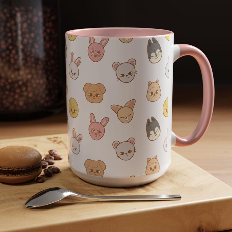 Puede incluir: Una taza de cer&aacute;mica blanca con un borde y un asa de color rosa. La taza presenta un patr&oacute;n repetido de caras de animales de dibujos animados, incluidos conejos, gatos, perros y p&aacute;jaros. Todos los animales sonr&iacute;en y tienen pelajes de diferentes colores.