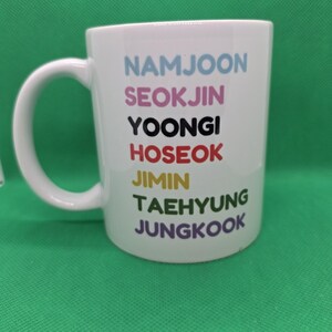 Pu&ograve; includere: Una tazza in ceramica bianca con sette nomi stampati in una colonna verticale in diversi colori: NAMJOON in azzurro, SEOKJIN in rosa, YOONGI in nero, HOSEOK in rosso, JIMIN in giallo, TAEHYUNG in verde e JUNGKOOK in viola.