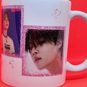 May include: White ceramic mug with a pink glitter border around two images of a man with black hair. The mug has a pink handle and the text "LOVE" is visible on the man's shirt in the left image.