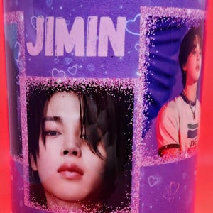 May include: A purple ceramic mug with a glittery design featuring a photo of a person with the name "Jimin" printed in pink letters.