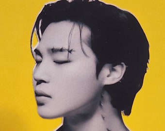 May include: A black and white photo of a person with short black hair. The person has their eyes closed and is looking down. The person has a tattoo of small birds on their neck.
