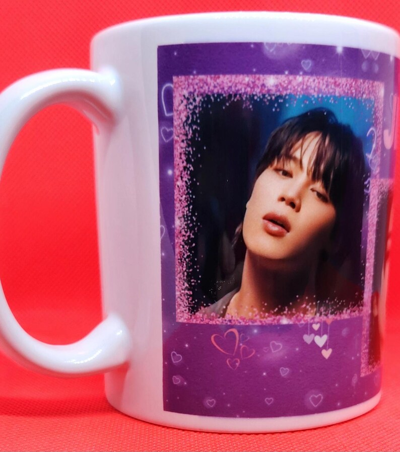 May include: White ceramic mug with a purple background and a pink glitter border. The mug features a photo of a person with dark hair and a light blue shirt. The photo is surrounded by pink hearts.