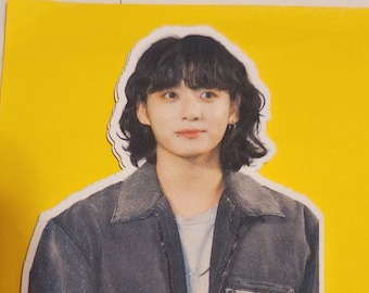 May include: A sticker of a person with long black hair wearing a dark blue jacket with the word "enfants" printed on the pocket.