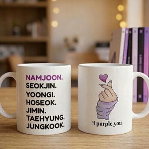Pu&ograve; includere: Due tazze in ceramica bianca. La prima tazza presenta i nomi NAMJOON, SEOKJIN, YOONGI, HOSEOK, JIMIN, TAEHYUNG e JUNGKOOK in nero, con NAMJOON in viola. La seconda tazza mostra una mano che fa un cuore con le dita e la scritta I purple you.