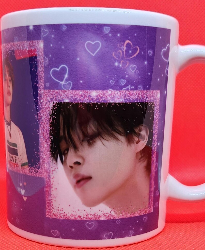 May include: White ceramic mug with a purple and pink design featuring a collage of images of a young man with black hair. The mug has a glittery pink border and hearts.