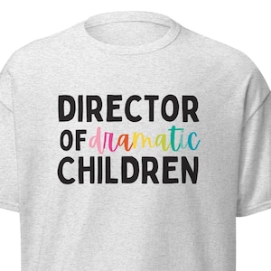 May include: Grey t-shirt with the text "DIRECTOR OF dramatic CHILDREN" in black lettering. The word "dramatic" is in rainbow colours.