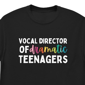 May include: Black t-shirt with white text that reads "Vocal Director of Dramatic Teenagers". The word "dramatic" is in rainbow colours.