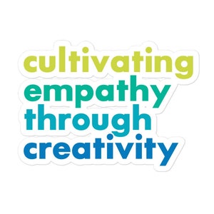 May include: A sticker with the text "cultivating empathy through creativity" in a gradient of blue, green, and yellow.