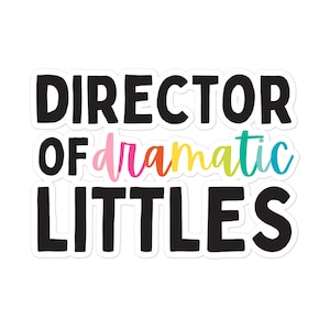 May include: Black and white sticker with the text "Director of dramatic littles". The word "dramatic" is in rainbow colours.