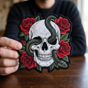 May include: Embroidered patch featuring a white skull with a green snake coiled around it, set against a backdrop of red roses and green leaves. The patch has a black border.