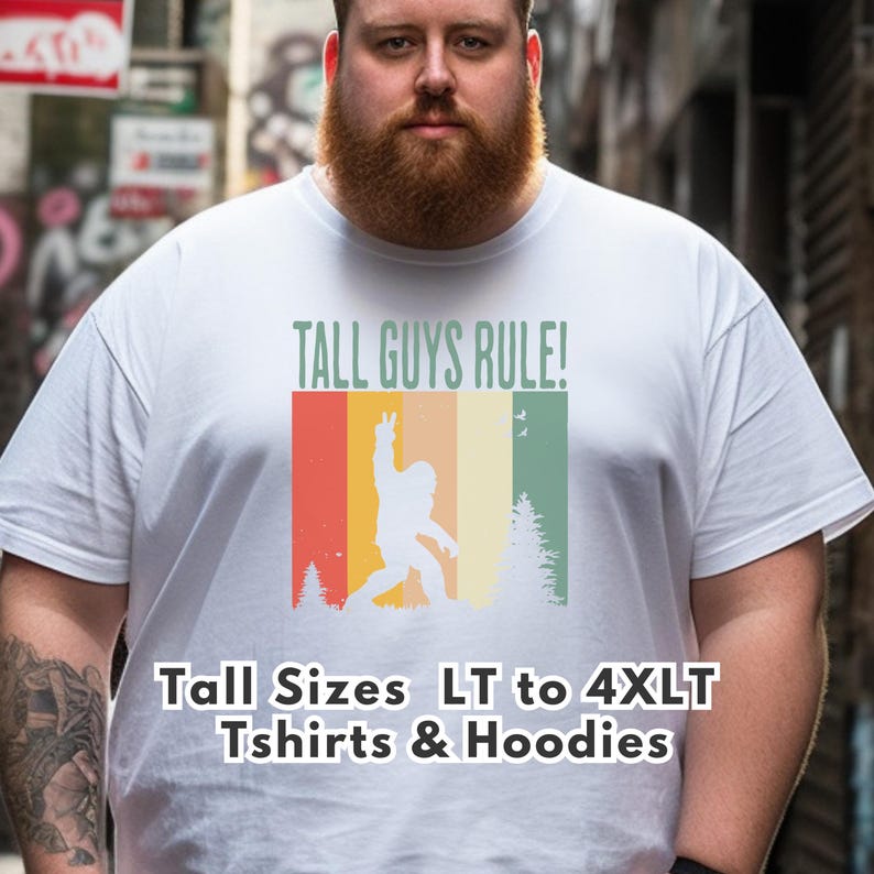 Puede incluir: Camiseta blanca con el texto "TALL GUYS RULE!" y un gr&aacute;fico retro de un Bigfoot haciendo el signo de la paz. El gr&aacute;fico tiene rayas rojas, naranjas, amarillas y verdes. La camiseta tambi&eacute;n tiene el texto "Tall Sizes LT to 4XLT Tshirts & Hoodies".