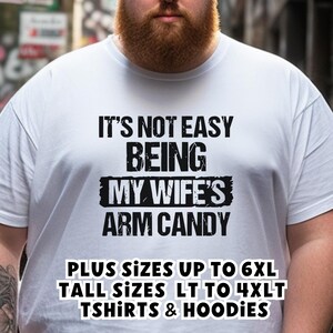 Funny Gift for Husband - a Tshirt with text saying "It's not easy being my wife's arm candy" - image includes a text overlay saying that we carry TShirts and Hoodies in Big sizes 3XL, 4XL, 5XL, and 6XL and Tall sizes LT, XLT, 2XLT, 3XLT, and 4XLT