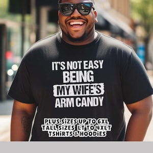 Funny Gift for Husband - a Black Tshirt with text saying "It's not easy being my wife's arm candy" - image includes a text overlay saying that we carry TShirts and Hoodies in Big sizes 3XL, 4XL, 5XL, and 6XL and Tall sizes LT, XLT, 2XLT, 3XLT, and 4XLT