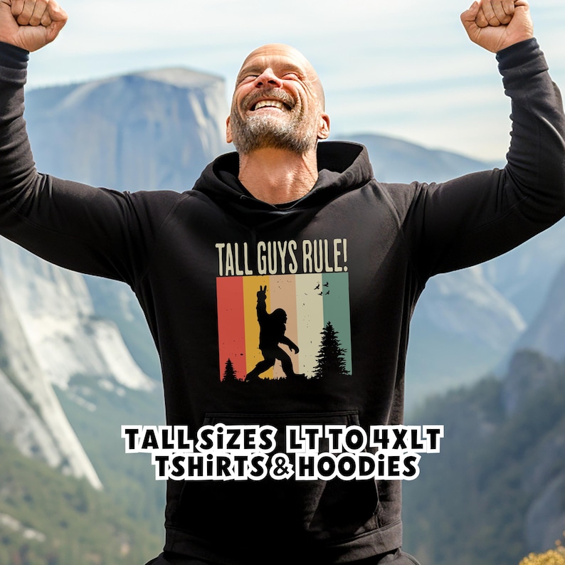 Puede incluir: Sudadera con capucha negra con el texto "TALL GUYS RULE!" y un gr&aacute;fico de Bigfoot en un dise&ntilde;o retro de bloques de color. La sudadera tambi&eacute;n tiene el texto "TALL SIZES LT TO 4XLT TSHIRTS & HOODIES".