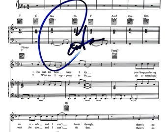 May include: A sheet music page featuring musical notation, guitar chord diagrams, and lyrics starting with "No matter how hard I try" and "What am I supposed to do". A dark blue handwritten signature is overlaid across the centre of the page.
