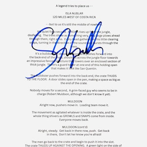 May include: A printed script page from a film featuring black text on a white background, detailing a scene at Isla Nublar. A prominent, bold blue ink signature is scrawled across the centre of the page, overlaying the written dialogue and narrative.
