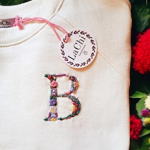Sudadera personalizada con inicial floral bordada a mano.