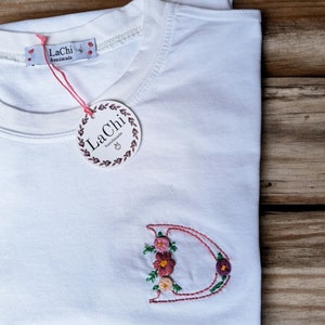 Camiseta personalizada com inicial floral bordada à mão.  Como presente, uma sacola de presente em algodão puro bordado.