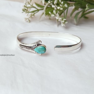 May include: A silver cuff bracelet with an open design. The bracelet features a turquoise stone set in a decorative setting. The text "Shreejaipurjewels92" is visible on the left side of the image. The bracelet is displayed on a white surface.