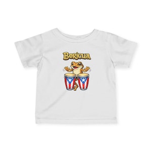 May include: White t-shirt featuring a cartoon frog playing bongo drums. The frog is brown and yellow, with the word "Boricua" above it. The drums are red, white, and blue, with the Puerto Rican flag design.