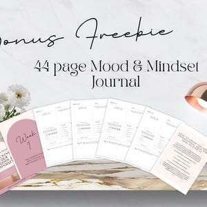 May include: A freebie 44-page Mood & Mindset Journal with a pink cover and the text "Tracking Your Moods & Mindset" on the front. The journal is open to a page with a mood tracker and the text "Week 1".