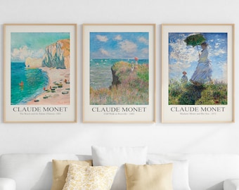 Puede incluir: Tres impresiones de arte enmarcadas de pinturas de Claude Monet. La primera impresión muestra una escena de playa con un acantilado rocoso y el texto "The Beach and the Palais d'Auteuil - 1883". La segunda impresión muestra una escena de acantilado con el texto "Cliff Walk at Pourville - 1882". La tercera impresión muestra una mujer y un niño caminando en un campo con el texto "Madame Monet and Her Son - 1875".