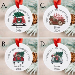 Pu&ograve; includere: Quattro ornamenti rotondi in ceramica bianca con nastri rossi. Ognuno presenta un veicolo con un albero di Natale, il testo THE YEAR I GOT MY DRIVER'S LICENSE, un nome e l'anno 2026. I disegni includono un'auto rossa, un camion rosso e uno grigio.