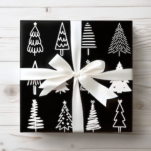 May include: A wrapped gift box with black wrapping paper featuring white Christmas tree designs. A wide white satin ribbon is tied around the box in a bow. The gift box is on a light wood surface.