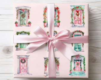 Könnte beinhalten: Geschenkpapier mit Aquarellillustrationen von festlichen Türen, die mit Kränzen und Girlanden geschmückt sind. Die Türen sind in Grün- und Rosatönen gehalten und vor einem hellrosa Hintergrund platziert. Ein großes, hellrosa Satinband ist um das Geschenk gebunden.