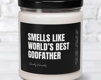 May include: A white candle with a black label that reads "Smells Like World's Best Godfather" with the text "Dandy Nomads" below. The candle is in a glass jar with a black lid.