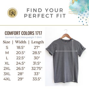 以下が含まれることがあります： 木製のハンガーに掛けられたグレーのComfort Colors 1717ヘビーウェイトTシャツ。画像には、Sサイズから4XLサイズまでの幅と長さのインチ単位のサイズチャートが含まれています。「FIND YOUR PERFECT FIT」というテキストも表示されています。