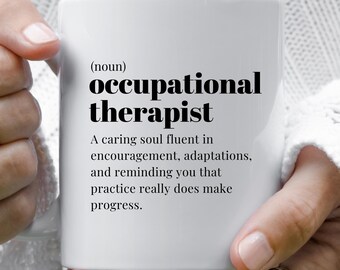 May include: White ceramic mug with the words "occupational therapist" in black, along with a definition and inspirational quote. The mug is held by a person.