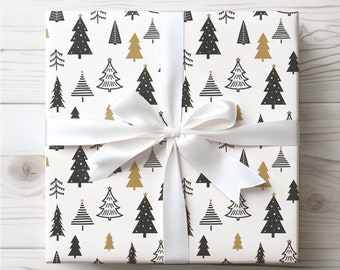 May include: A wrapped gift with a white satin ribbon. The wrapping paper features a repeating pattern of black and gold Christmas trees on a cream background. The gift is presented on a light wood surface.