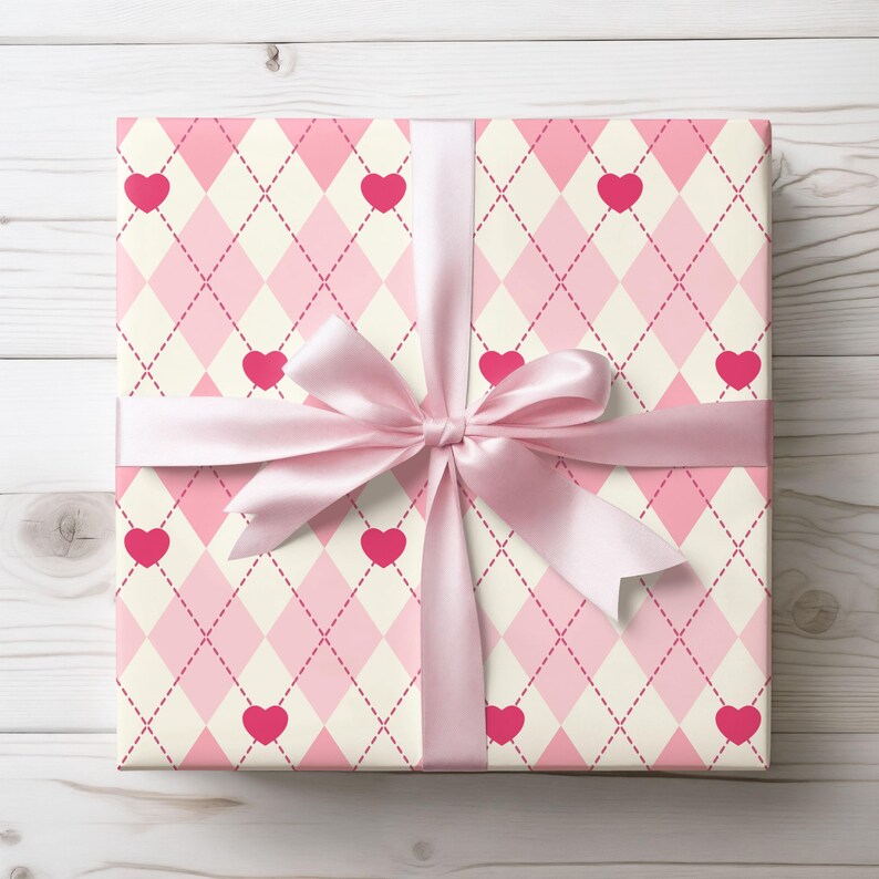 May include: A pink and white gift box with a pink ribbon and a heart pattern. The box is wrapped in a pink and white argyle pattern with pink hearts.