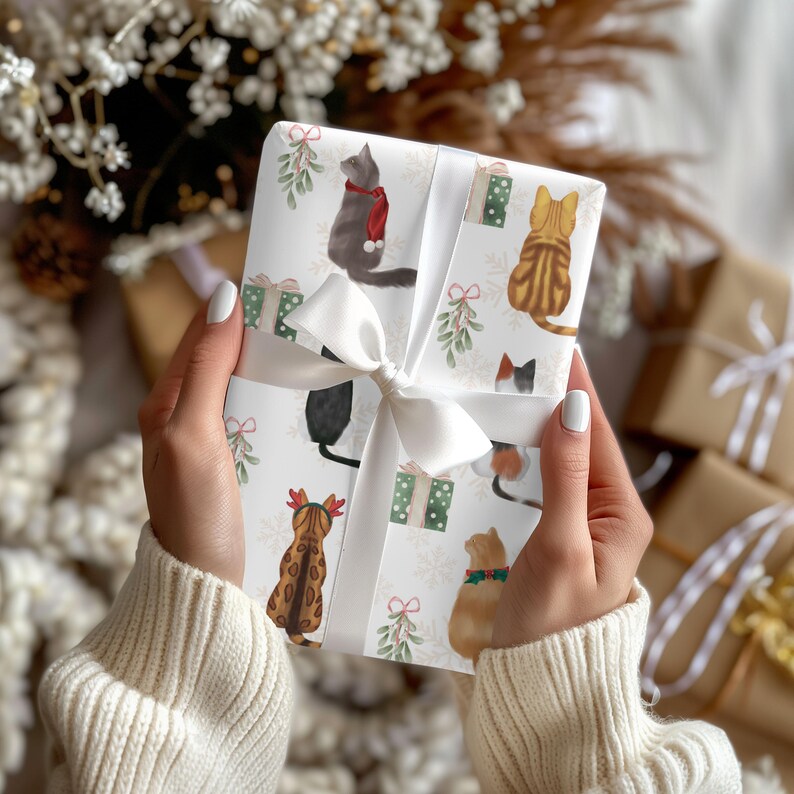 K&ouml;nnte beinhalten: Ein Geschenk mit wei&szlig;em Band, verziert mit einem sich wiederholenden Muster aus Aquarellkatzen in festlicher Kleidung. Die Katzen sind in verschiedenen Farben, darunter Grau, Braun und Schwarz, mit Weihnachtsaccessoires. Gr&uuml;ne Geschenkboxen und Mistelzweige erg&auml;nzen das Design.