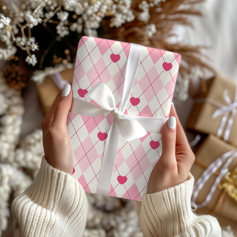 May include: A pink and white gift wrap with a pink heart pattern. The gift is wrapped with a white ribbon and bow.