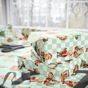 Puede incluir: Cajas de regalo navide&ntilde;as envueltas en papel a cuadros verde claro y blanco. El papel presenta ilustraciones vintage de Pap&aacute; Noel, ni&ntilde;os, gatos y &aacute;rboles de Navidad. Se ven unas tijeras y un rollo de papel de regalo.