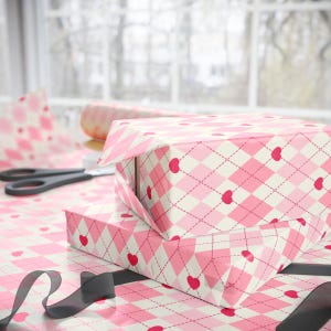 May include: Two pink and white gift boxes with a pink and white argyle pattern and red hearts. The boxes are wrapped in pink and white patterned paper.