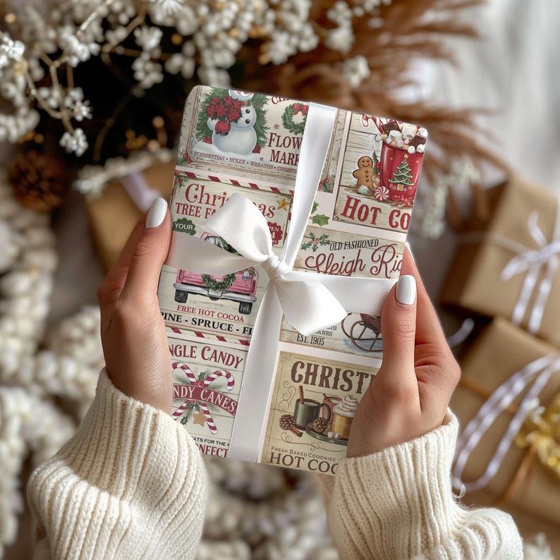 May include: A wrapped gift with a festive Christmas-themed paper featuring images of a snowman, a red truck, candy canes, and hot cocoa. The gift is tied with a white satin ribbon and bow. The paper includes the text "Christmas Tree Farm" and "Hot Cocoa".